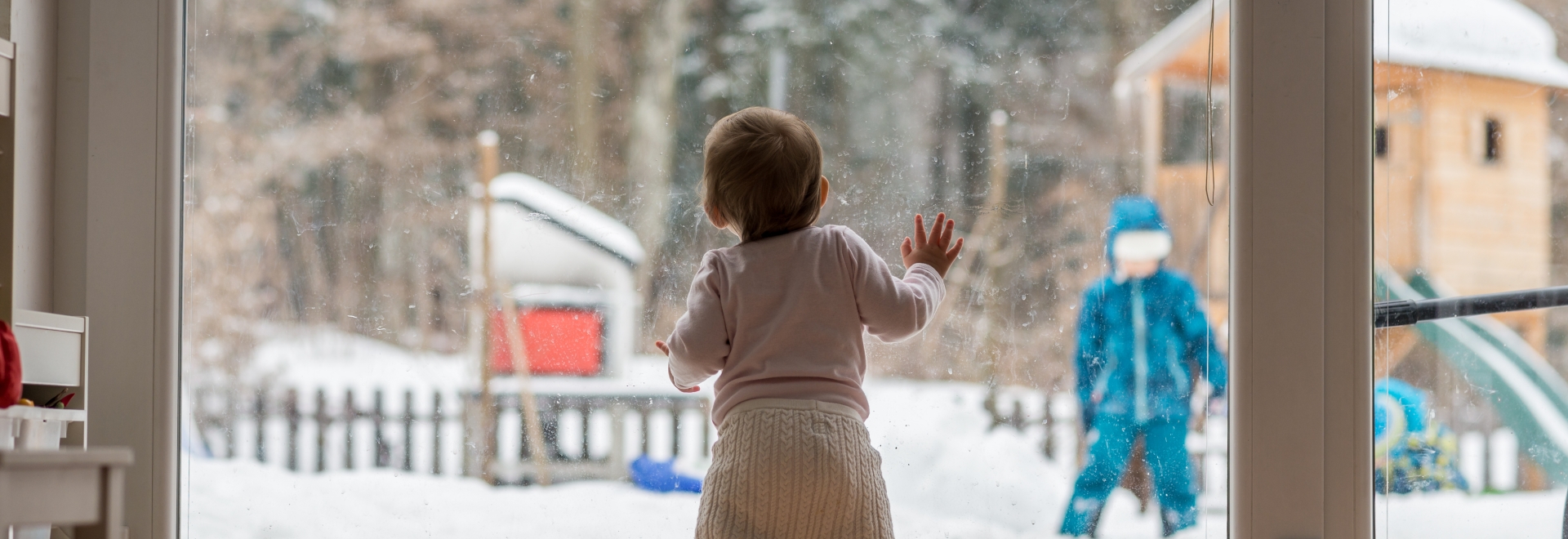 baby looking out the window at the snow