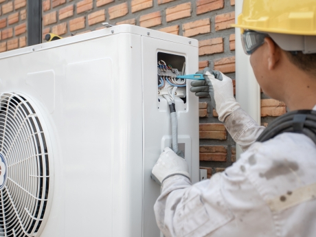 man working on heat pump outdoor unit